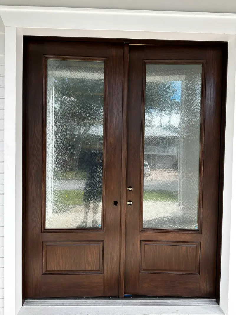 Stained wood double entry doors with frosted glass panels and white trim